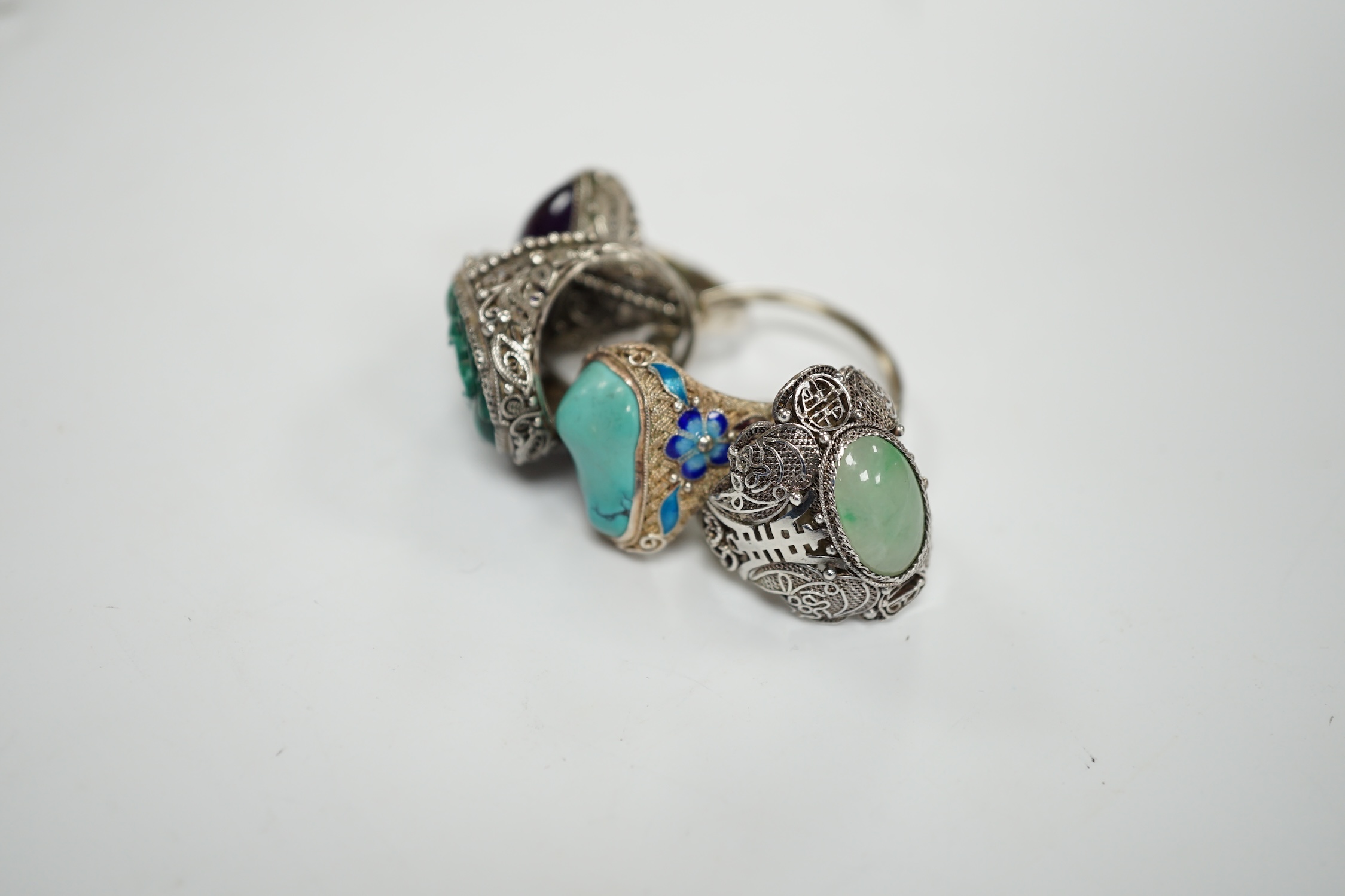 Four assorted Chinese white metal filigree and gem set rings, including turquoise and amethyst.